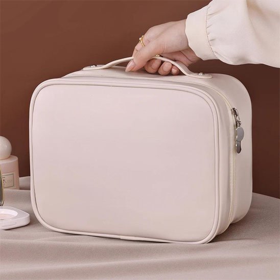Trousse maquillage beige femme la tiens par la lanière
