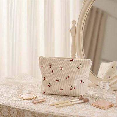 Trousse maquillage en tissu motif cerise poser sur commode